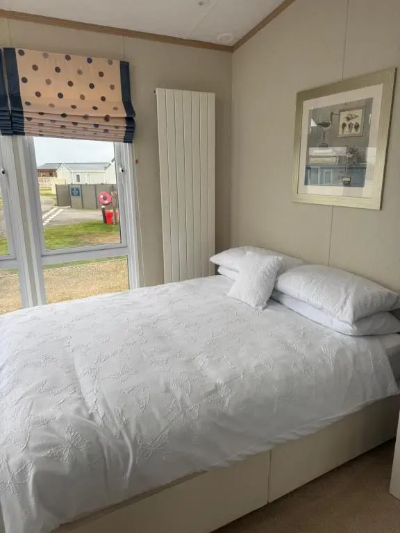 a bedroom with a white bed with a window at Aurora luxury beach lodge in Lossiemouth