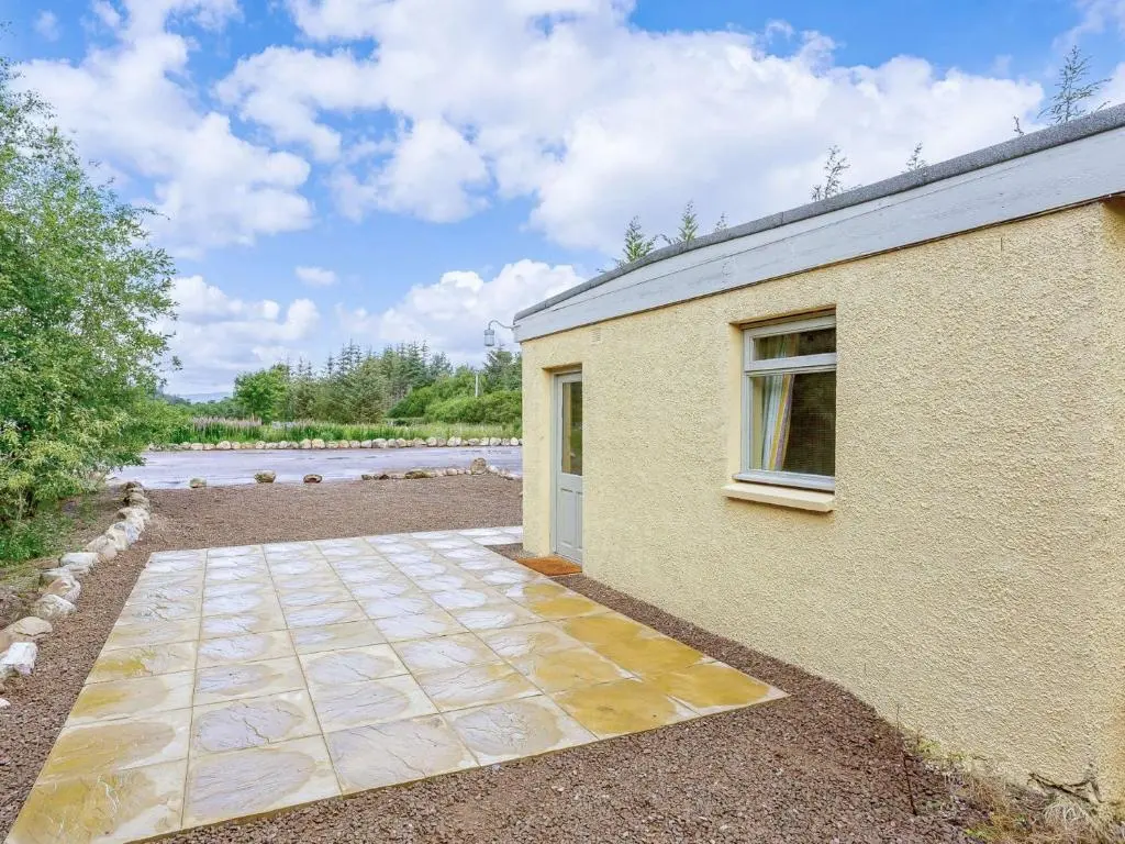 a building with a walkway next to a river at 1 Bed in Balblair 89058 in Culrain