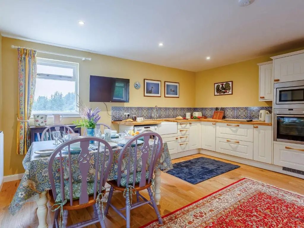 a kitchen with a table and chairs and a kitchen with yellow walls at 1 Bed in Balblair 89058 in Culrain