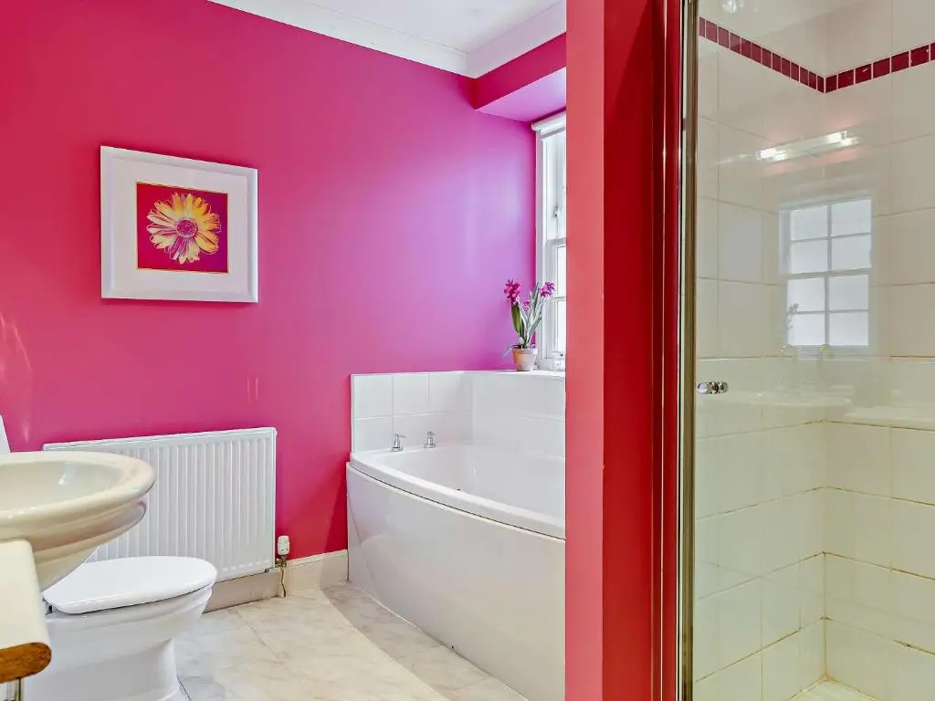 a bathroom with pink walls and a toilet and a bath tub at 3 Bed in Conon Bridge CA388 in Cononbridge