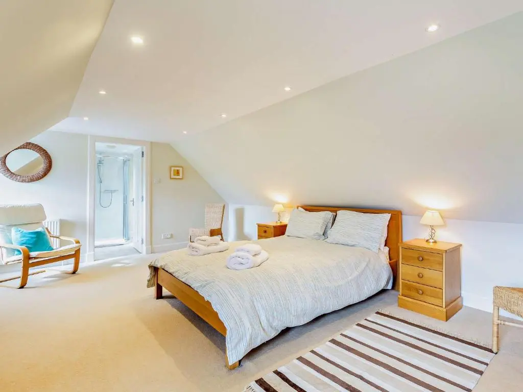 a bedroom with a large bed and a chair at 3 Bed in Conon Bridge CA388 in Cononbridge
