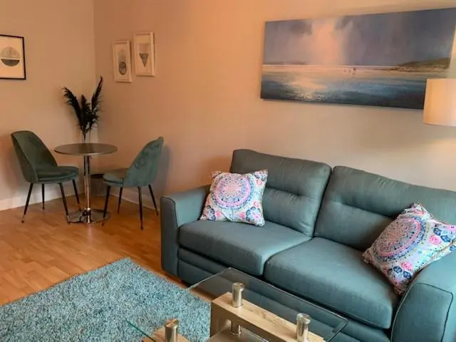 a living room with a blue couch and a table at Modern One Bedroom Apartment in Lossiemouth