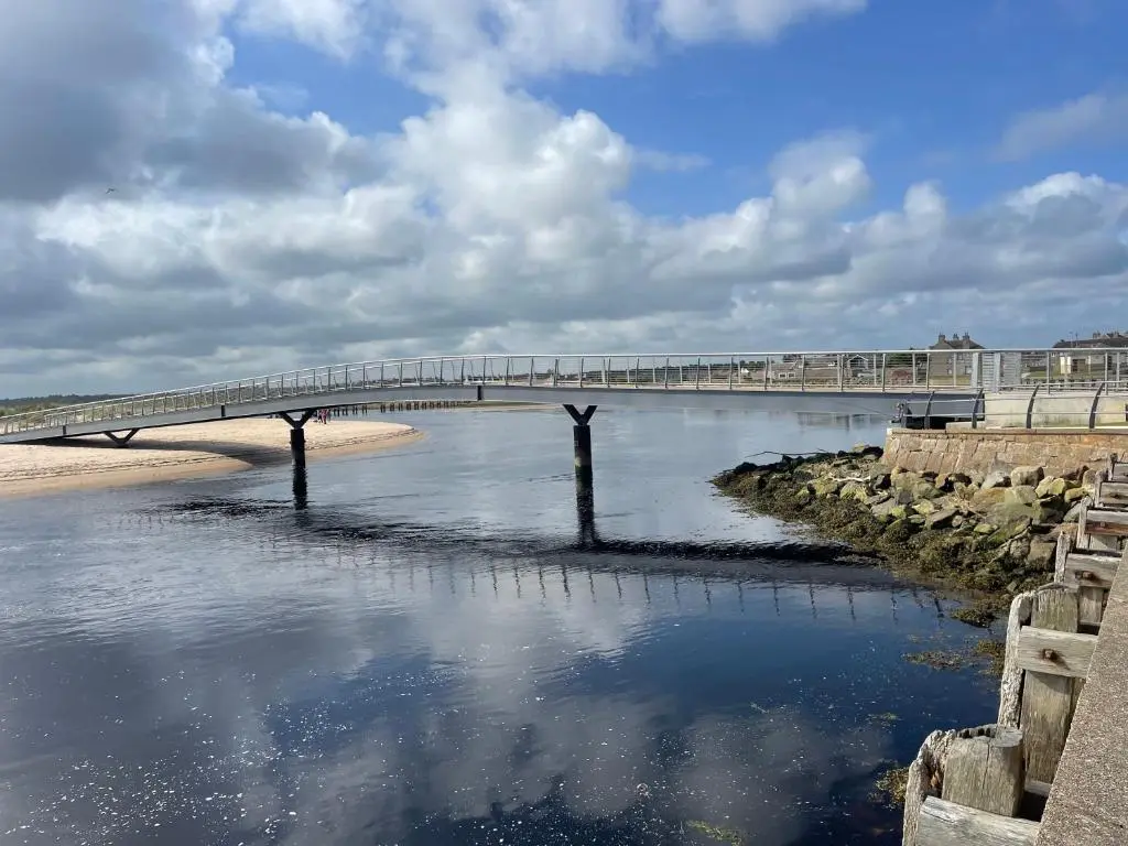 a bridge over a body of water next to a beach at Modern One Bedroom Apartment in Lossiemouth