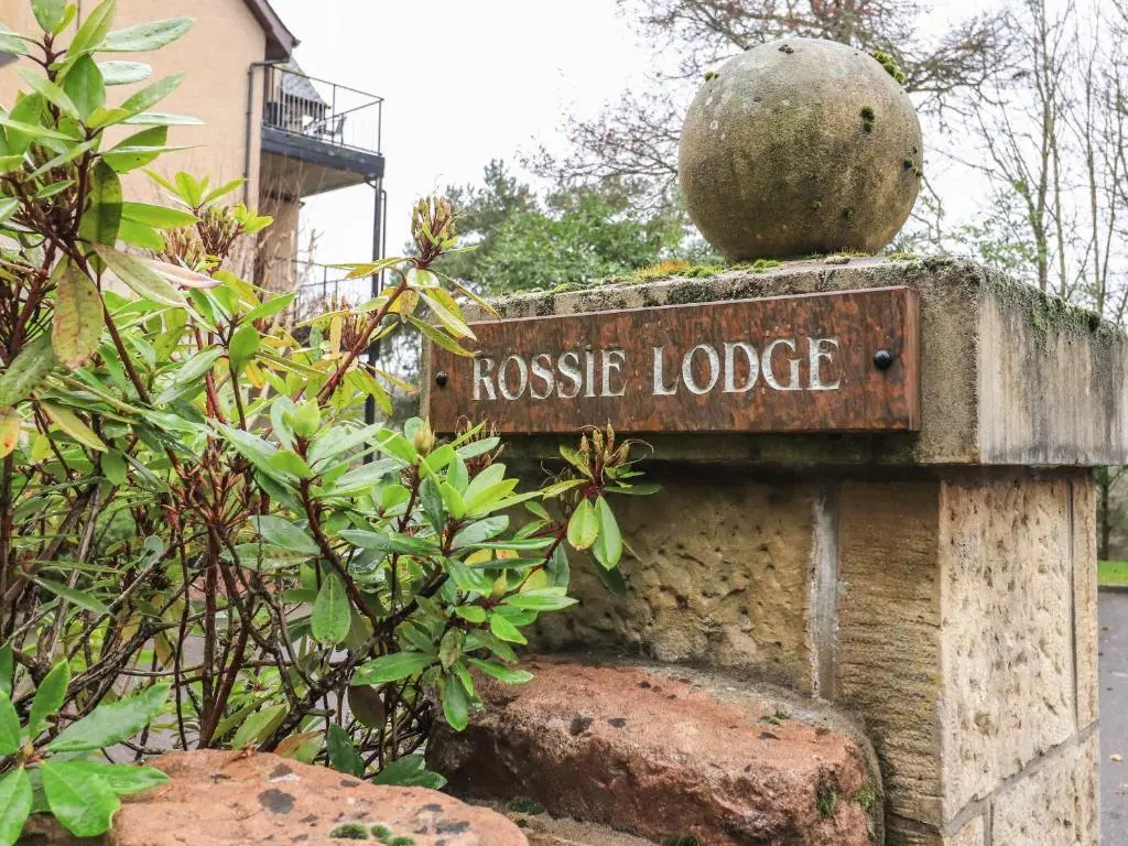 a sign for a house lodge in a garden at Rossie Lodge in Inverness