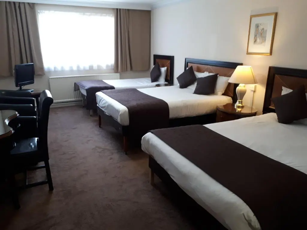a hotel room with three beds and a window at Britannia Hotel Aberdeen in Aberdeen