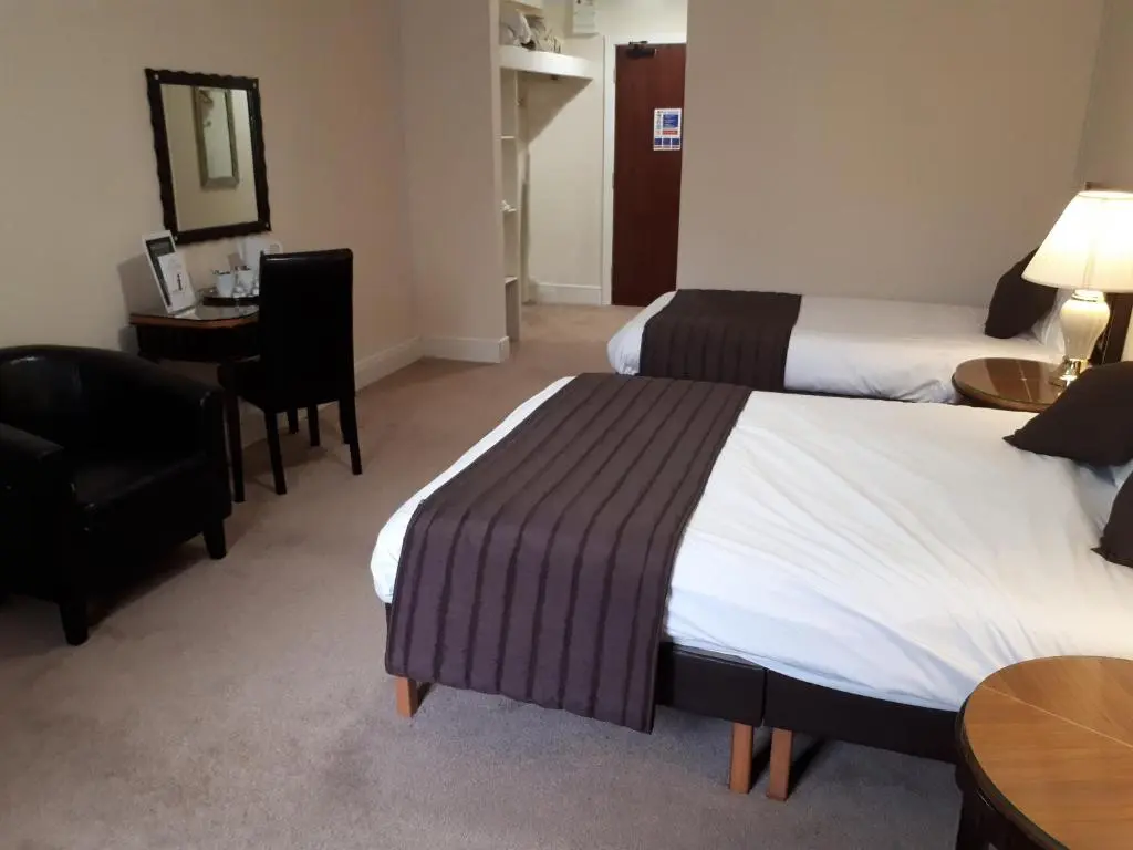 a hotel room with two beds and a desk at Britannia Hotel Aberdeen in Aberdeen