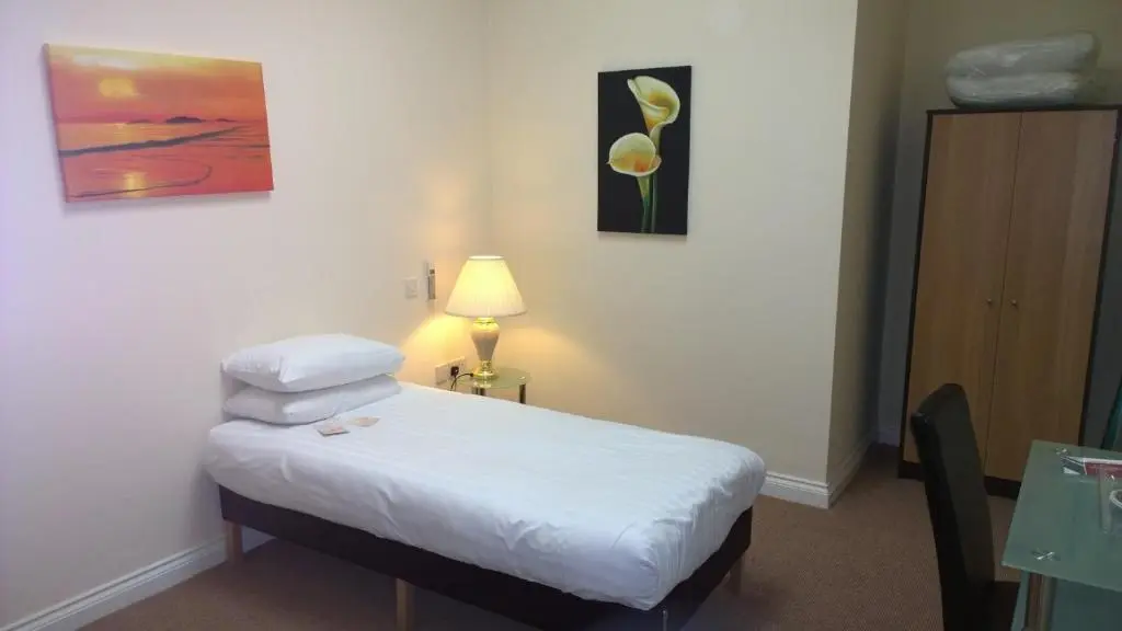 a room with a bed and a table with a lamp at Britannia Hotel Aberdeen in Aberdeen