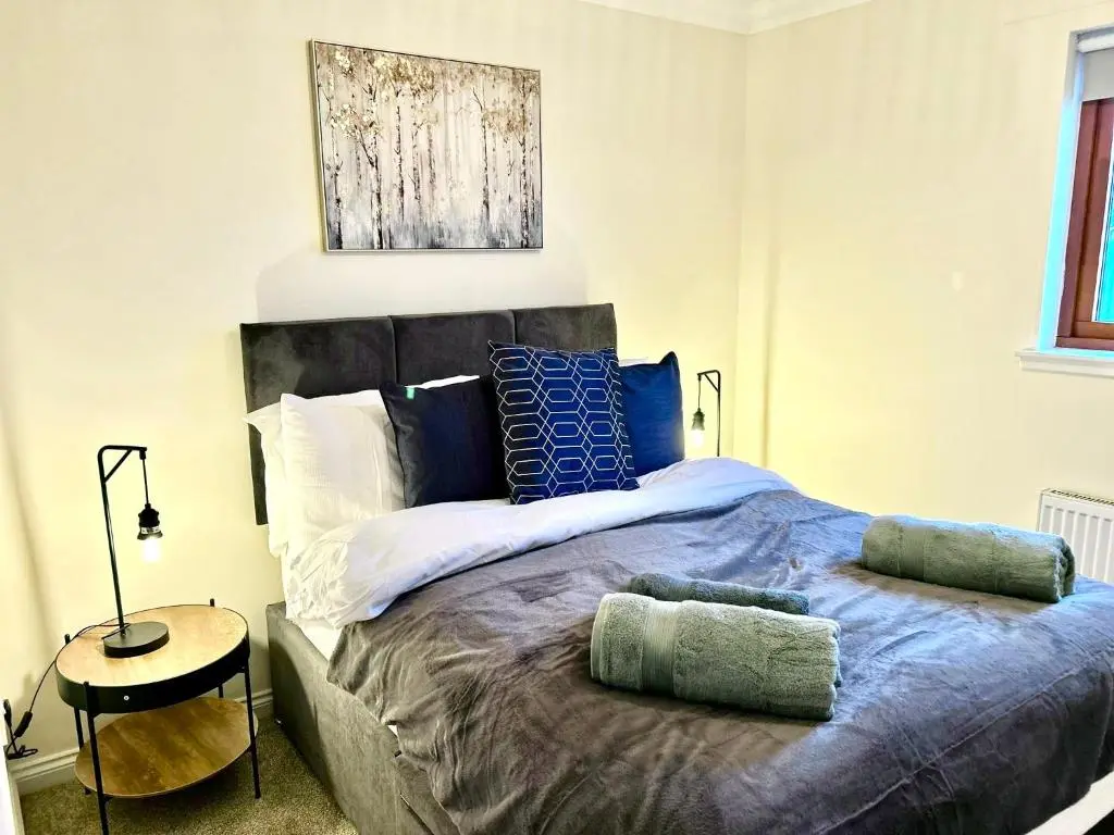 a bedroom with a large bed with blue pillows at Central Cosy Riverview Apartment 2 bed, 2 bath, Free Parking / WiFi in Inverness