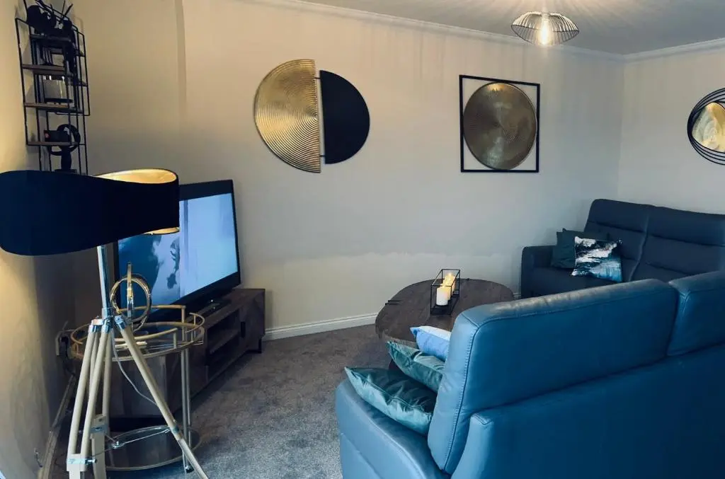 a living room with a blue couch and a tv at Central Cosy Riverview Apartment 2 bed, 2 bath, Free Parking / WiFi in Inverness