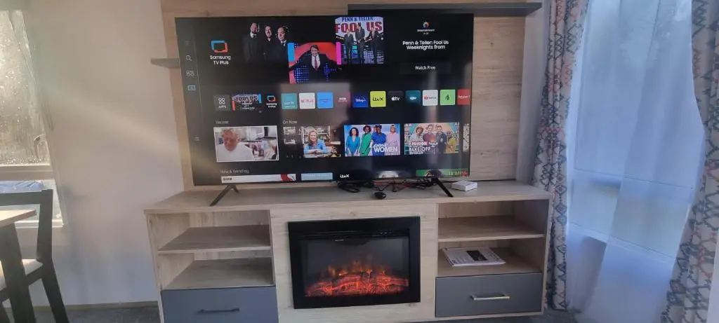 a entertainment center with a fireplace and a tv at Lynton lodges ATLAS in Evanton