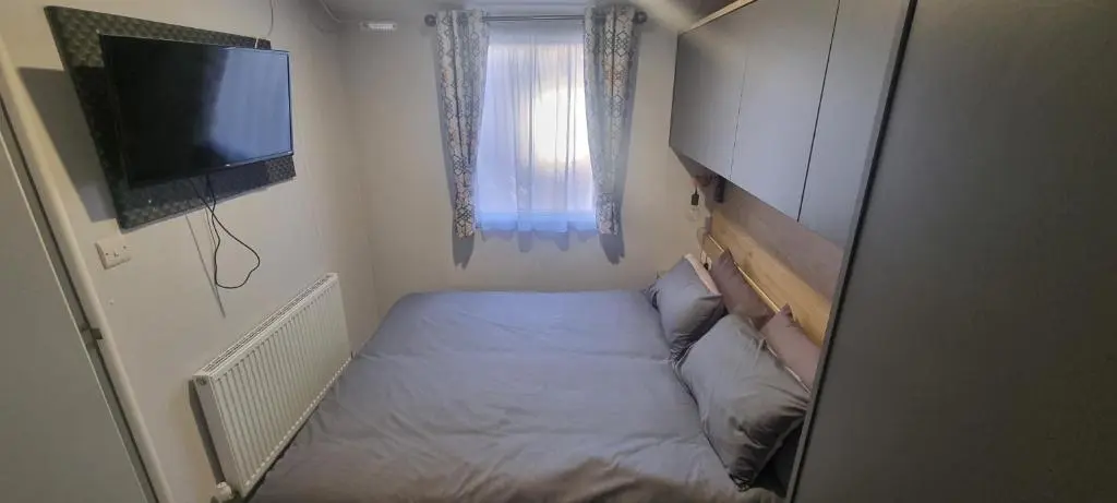 a small bedroom with a bed and a flat screen tv at Lynton lodges ATLAS in Evanton