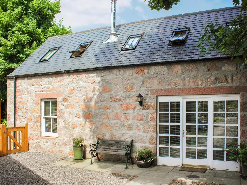 a stone building with a bench in front of it at Sycamore Cottage - Uk45923 in Ballater