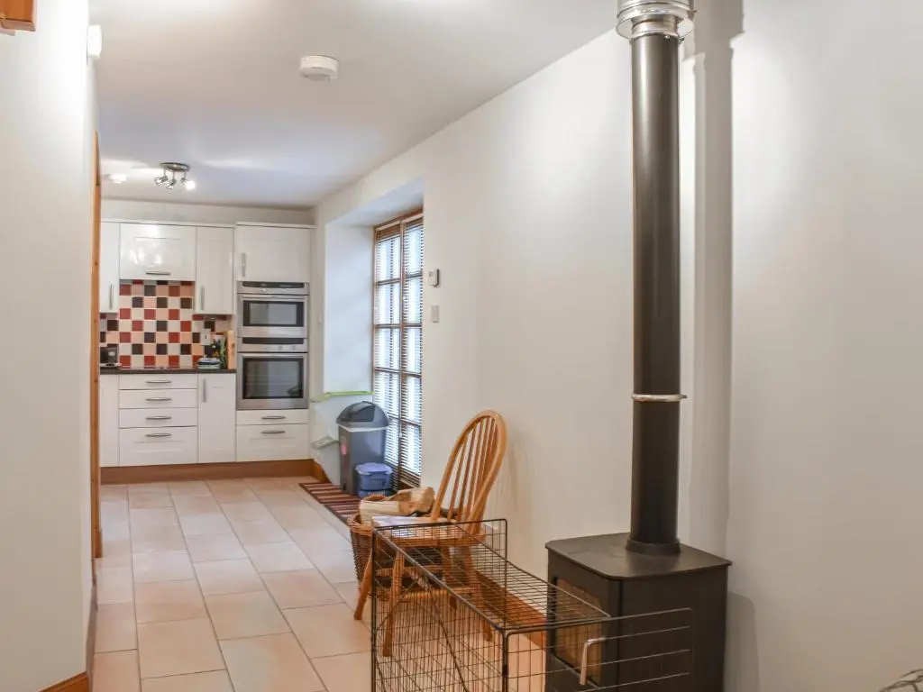 a kitchen with white cabinets and a black stove at Sycamore Cottage - Uk45923 in Ballater