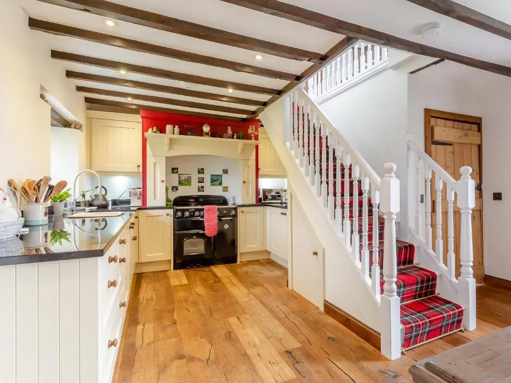 a kitchen with wooden floors and white walls and a staircase at 2 bed in Loch Ness CA315 in Drumnadrochit