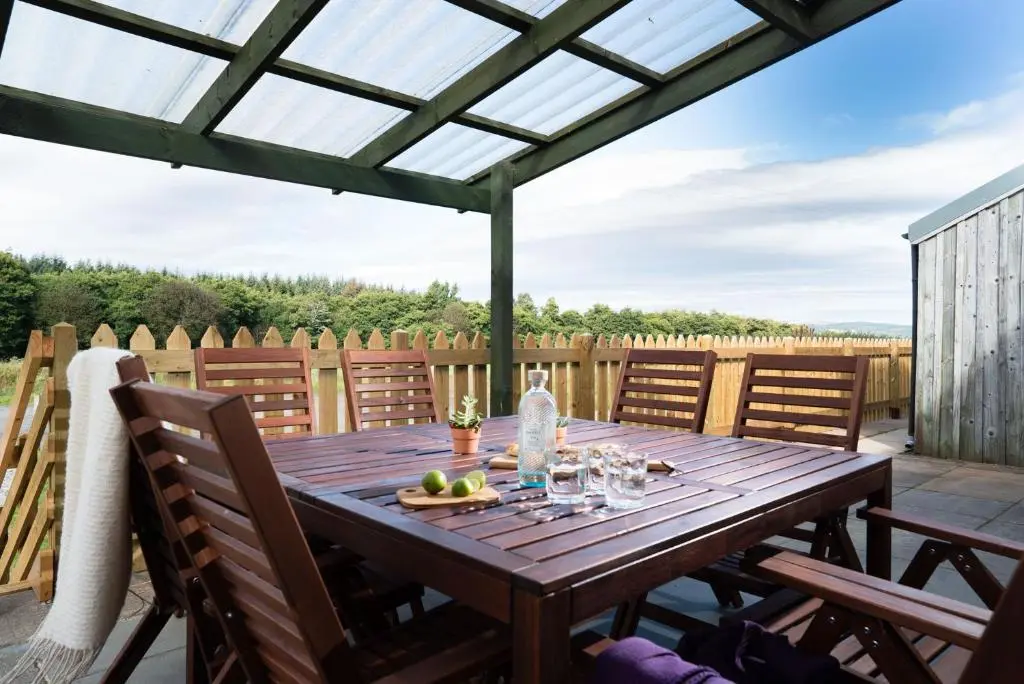 a wooden table on a patio with a fence at Nethy Station - Seasgair Lodges in Nethy Bridge