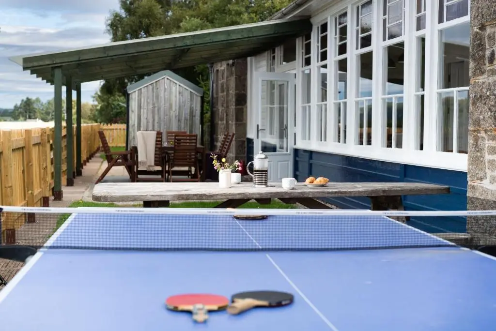 a ping pong table on the patio of a house at Nethy Station - Seasgair Lodges in Nethy Bridge