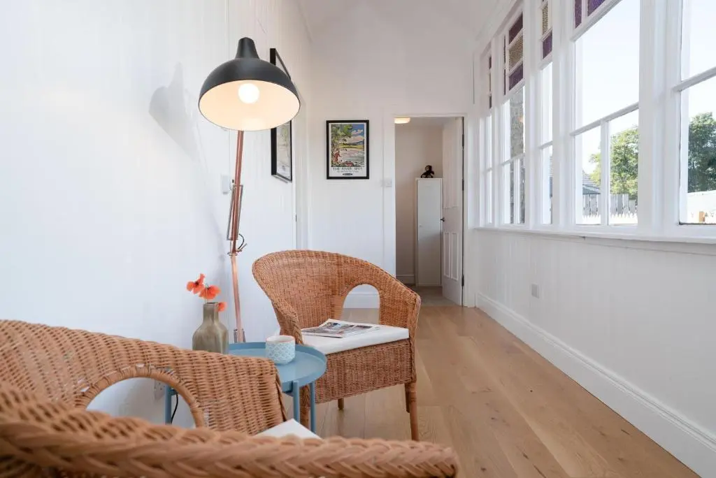 a hallway with wicker chairs and a table and a lamp at Nethy Station - Seasgair Lodges in Nethy Bridge