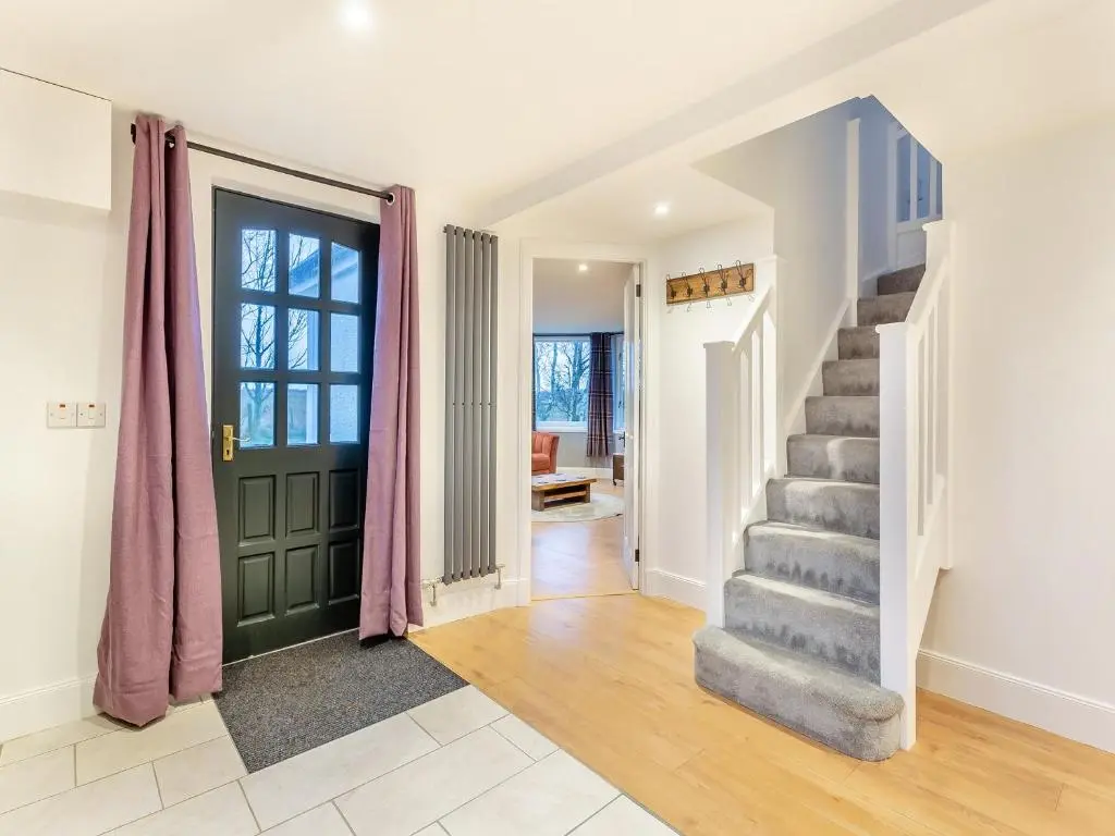 a hallway with a green door and stairs in a house at East Tarrel Cottage in Portmahomack