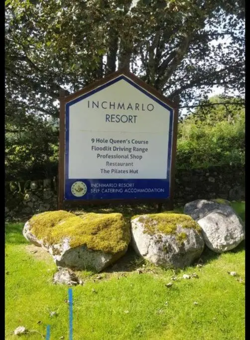 a sign in a field with some rocks at Apartment in Queens Court, Banchory in Inchmarlo