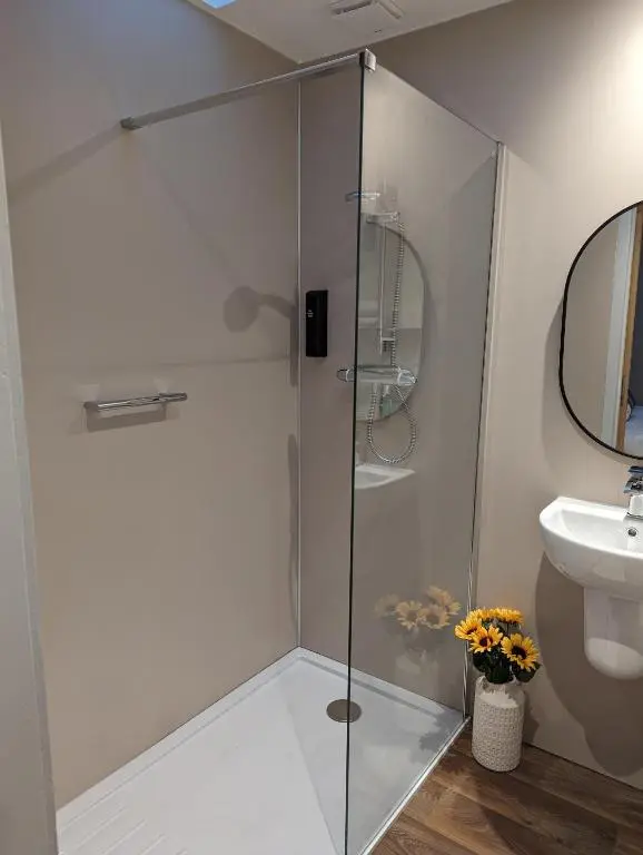 a shower with a glass door next to a sink at The Coo Shed in Inverness