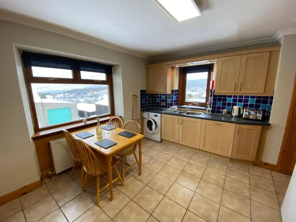 a kitchen with a table and chairs and a sink at Lyngarrie in Dufftown