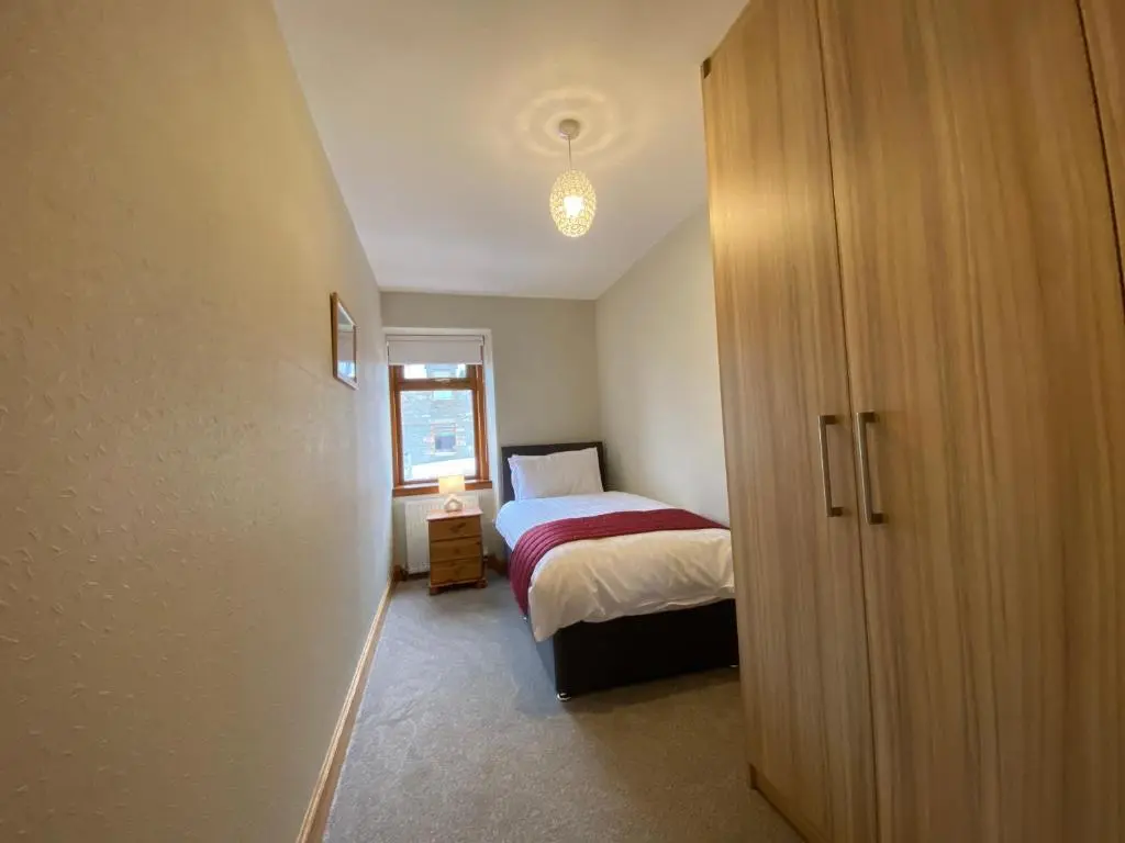 a small bedroom with a bed and a closet at Lyngarrie in Dufftown