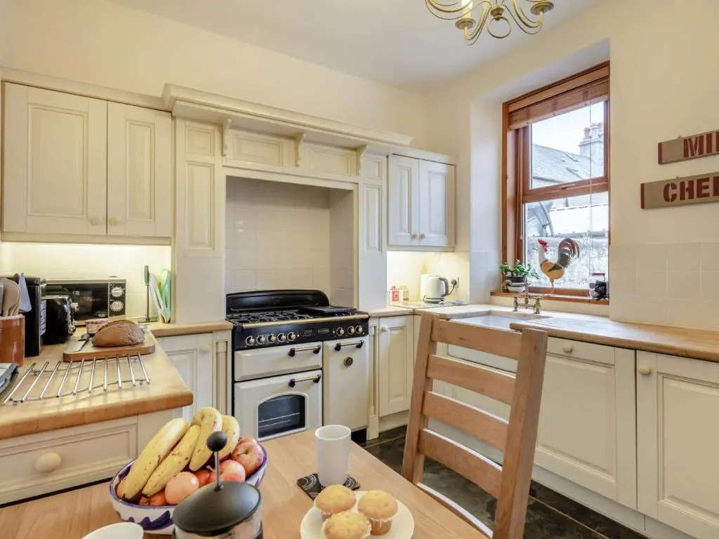 a kitchen with white cabinets and a table with a bowl of food at 3 Bed in Buckie 89824 in Buckie