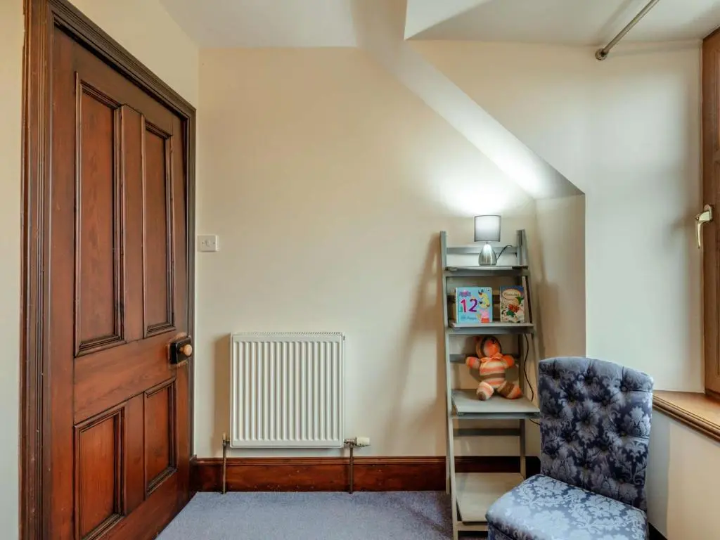 a room with a chair and a book shelf at 3 Bed in Buckie 89824 in Buckie