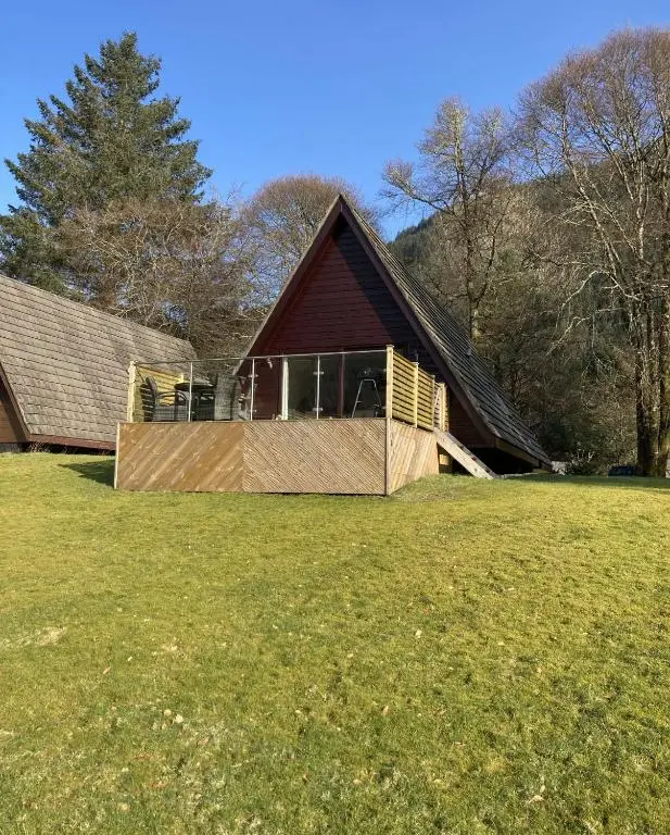 a large house with a gambrel roof on a field at Lodge 24 in Spean Bridge