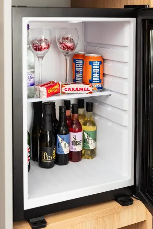 an open refrigerator filled with drinks and wine glasses at Caledonian Hotel 'A Bespoke Hotel\u2019 in Ullapool