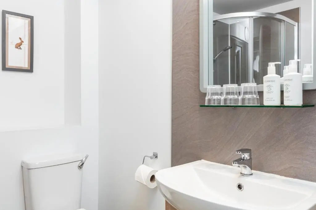 a bathroom with a white sink and a mirror at Caledonian Hotel 'A Bespoke Hotel\u2019 in Ullapool