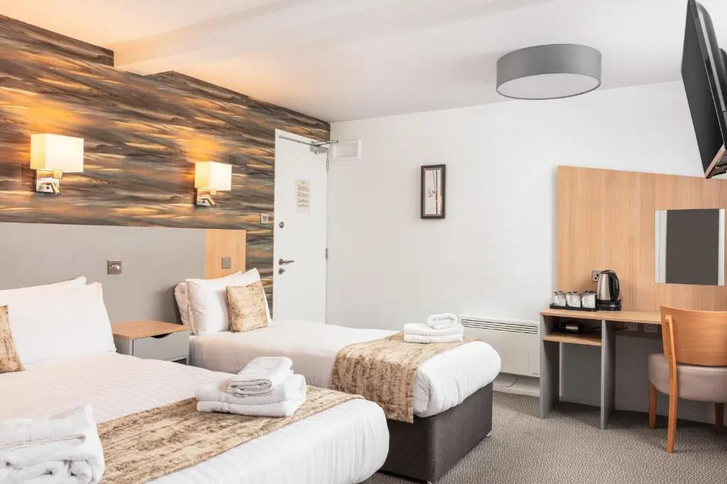 a hotel room with two beds and a desk at Caledonian Hotel 'A Bespoke Hotel\u2019 in Ullapool