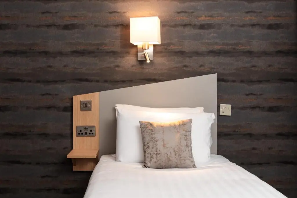 a bedroom with a bed with a pillow and a lamp at Caledonian Hotel 'A Bespoke Hotel\u2019 in Ullapool