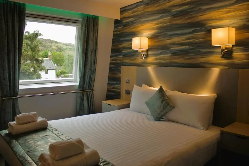 a hotel room with a bed with two teddy bears on it at Caledonian Hotel 'A Bespoke Hotel\u2019 in Ullapool