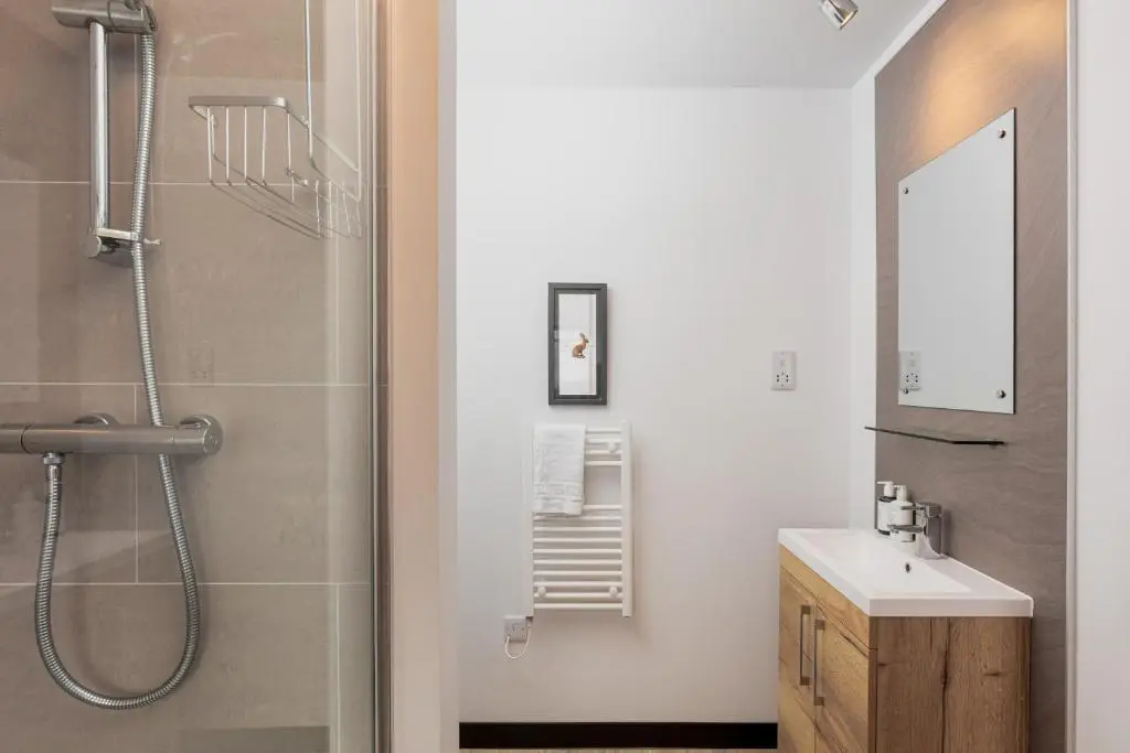 a bathroom with a shower and a sink and a mirror at Caledonian Hotel 'A Bespoke Hotel\u2019 in Ullapool
