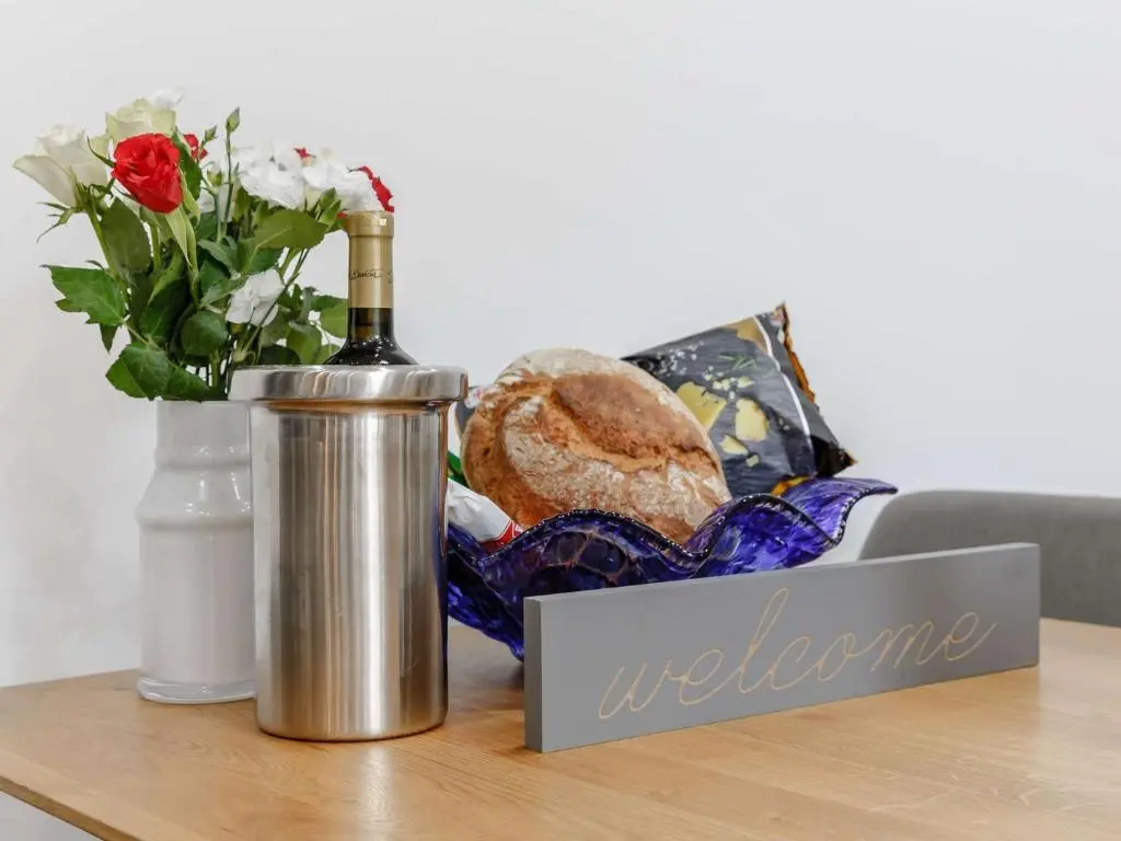 a bottle of wine and a vase of flowers on a table at 4 Bed in Wick 91390 in Wick