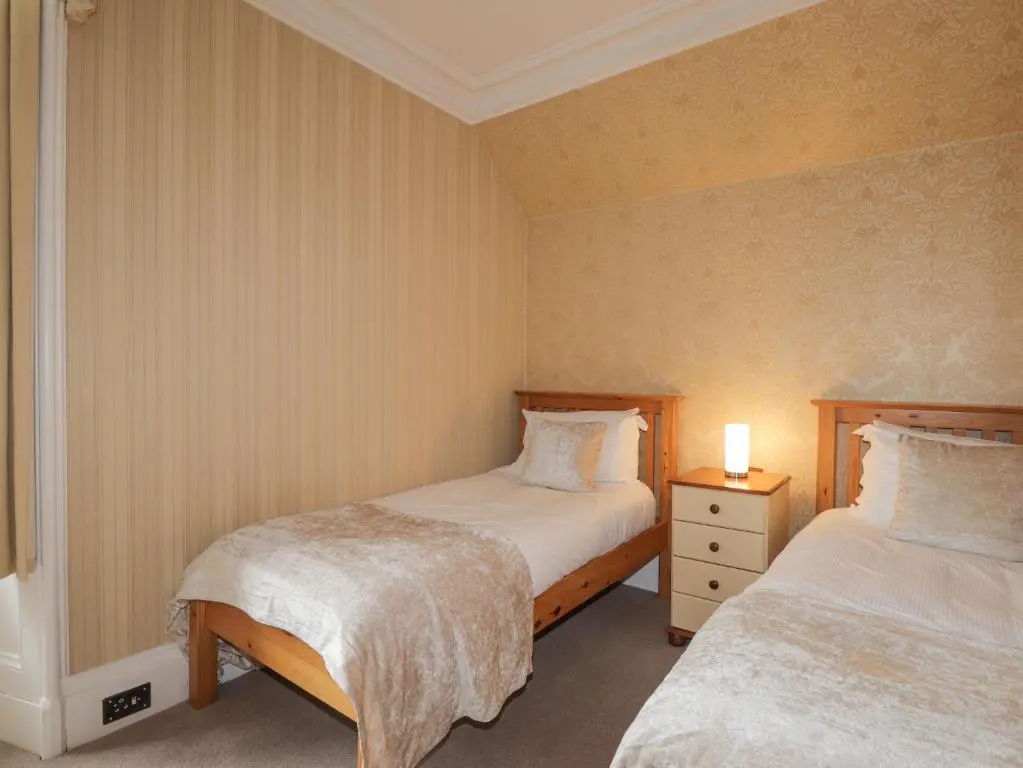 a bedroom with two beds and a lamp on a night stand at Arden House in Kingussie