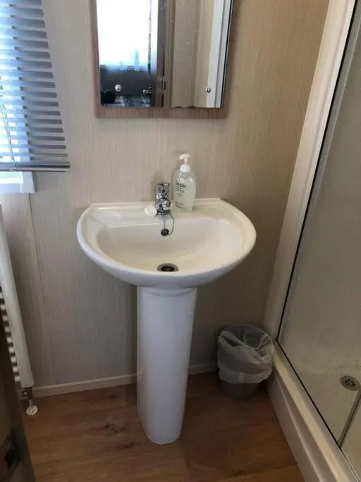 a bathroom with a white sink and a mirror at Coorie Nook, Chalet 103 in Aviemore