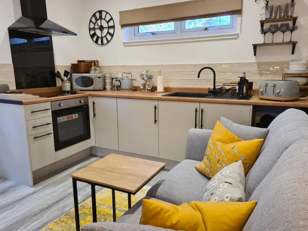 a living room with a couch and a kitchen at Findon Nook in Culbokie