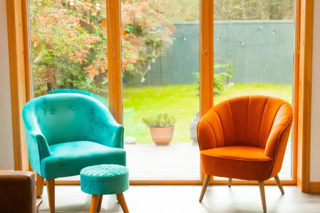 two chairs and a stool in front of a window at Woodhaus Aviemore Lodge in Aviemore