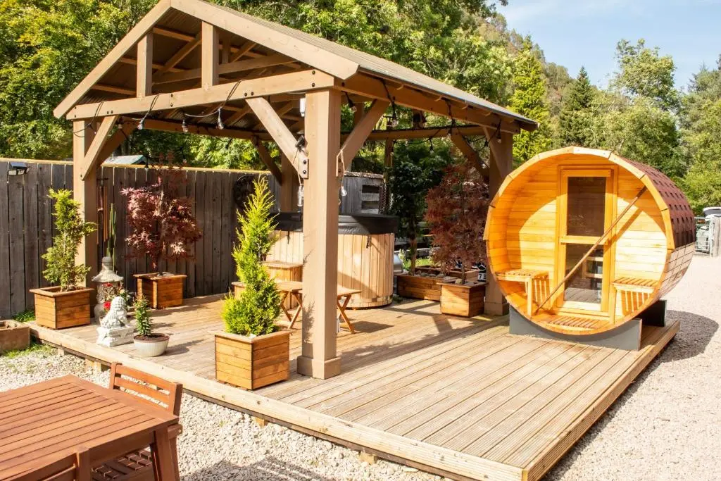 a wooden deck with a gazebo in a backyard at Woodhaus Aviemore Lodge in Aviemore