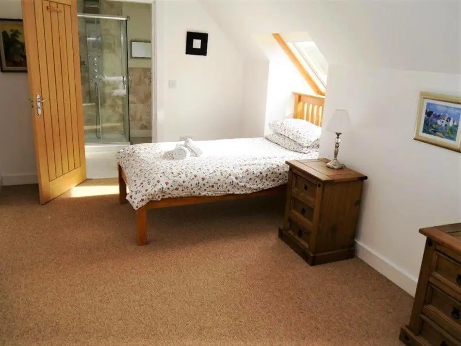 a bedroom with a bed and a dresser and a window at Osprey Cottage in Aviemore