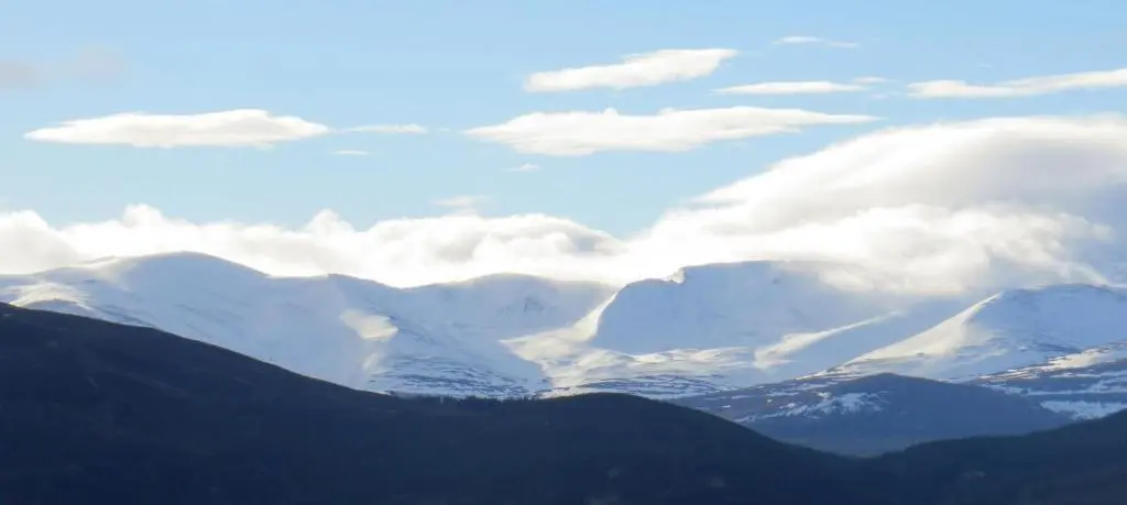 a view of snow covered mountains with clouds in the sky at Sycamore Cottage in Boat of Garten