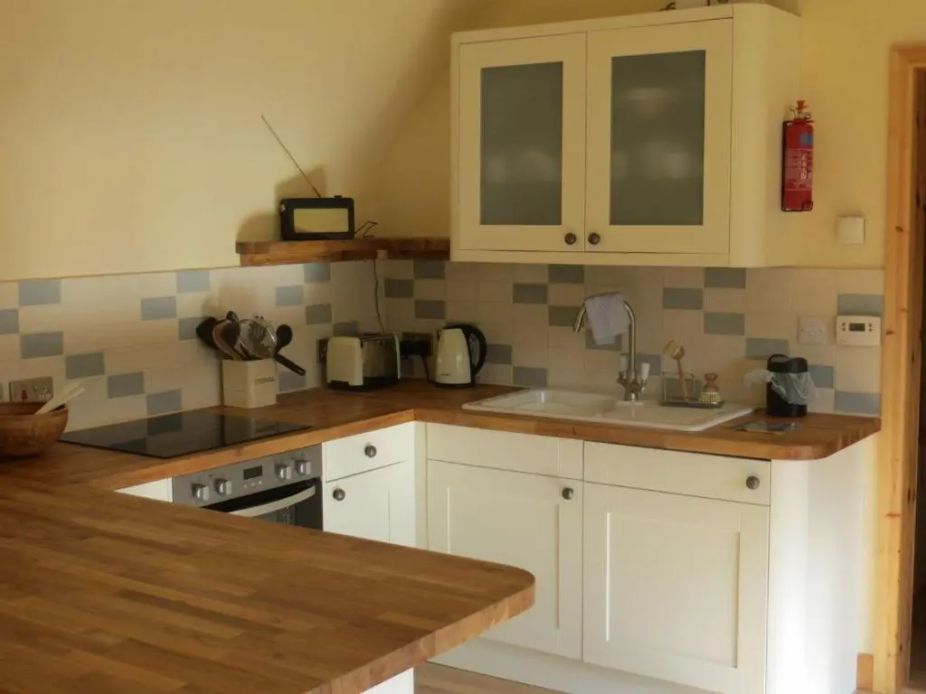 a kitchen with white cabinets and a sink at Sycamore Cottage in Boat of Garten