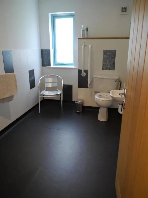 a bathroom with a toilet and a sink and a chair at Ptarmigan Cottage in Aviemore