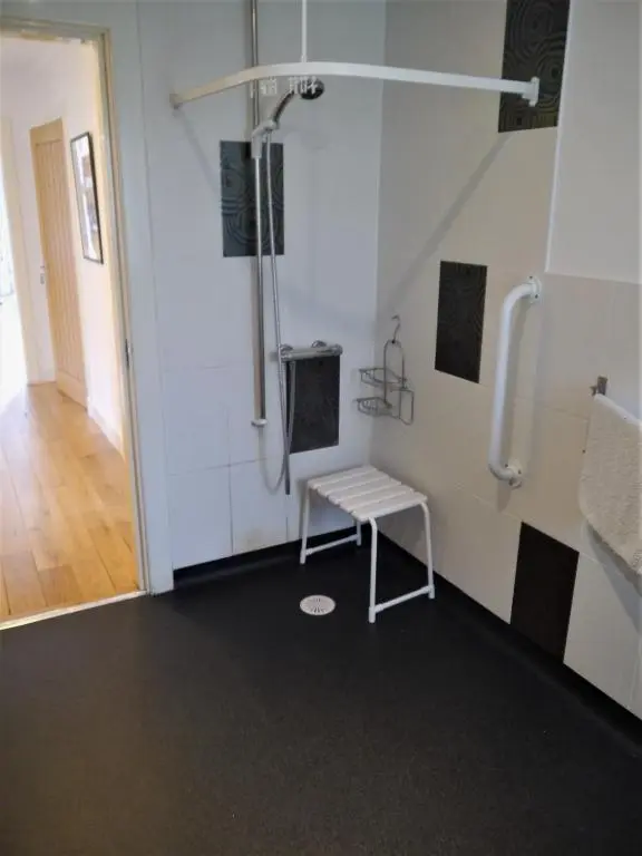 a shower stall with a bench in a room at Ptarmigan Cottage in Aviemore