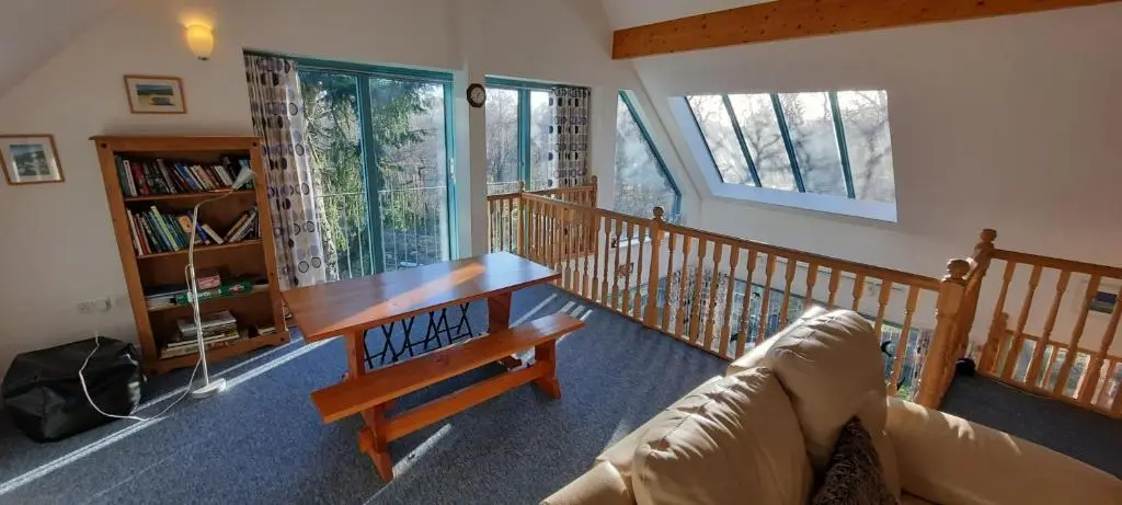 a living room with a couch and a wooden table at Ptarmigan Cottage in Aviemore