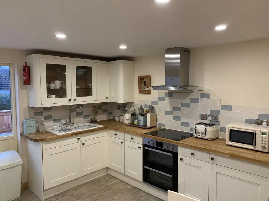 a kitchen with white cabinets and a stove top oven at Locheil Apartment in Boat of Garten