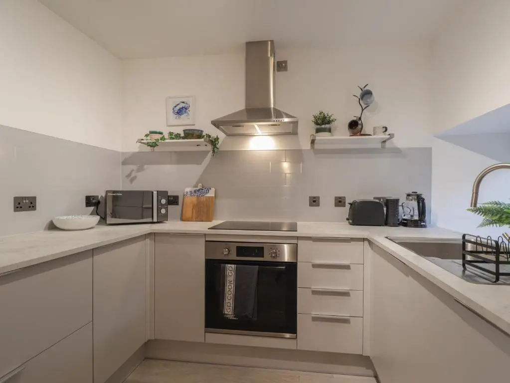 a kitchen with white cabinets and a stove top oven at Flat 4, The Byre in Cromarty