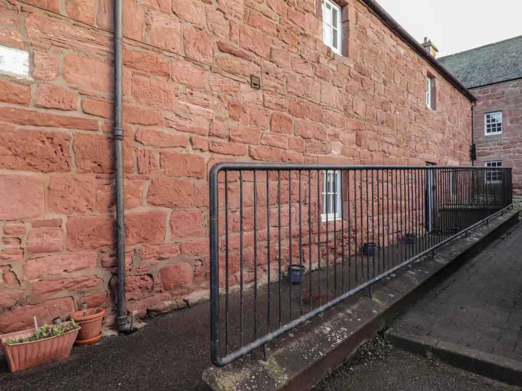 a brick wall with a gate next to a building at Flat 4, The Byre in Cromarty